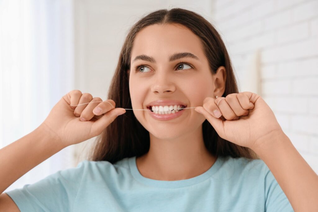 teenager flossing her teeth