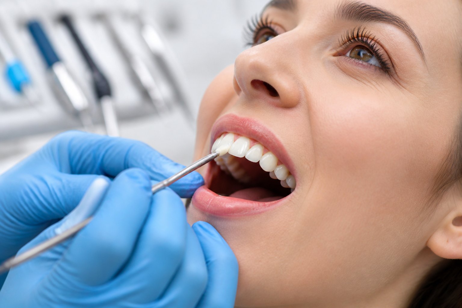 Dentist applying dental bonding material to a patient's front tooth in a dental clinic.